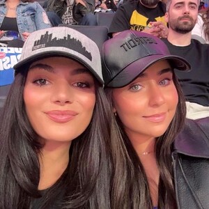K&ouml;nnte beinhalten: Zwei Personen tragen Baseballkappen. Eine ist grau mit dem Schriftzug "DETROIT" und Skyline, die andere schwarz. Sie befinden sich in einer &uuml;berf&uuml;llten Arena, im Hintergrund sind viele Zuschauer zu sehen.