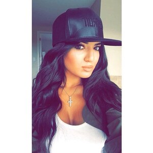 K&ouml;nnte beinhalten: Schwarze Baseballkappe aus Leder mit dem Wort "Detroit" auf der Vorderseite. Die Kappe hat einen flachen Schirm. Eine Person mit langen, dunklen Haaren tr&auml;gt die Kappe. Ein silberner Kreuzanh&auml;nger ist sichtbar.