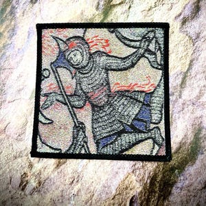 May include: A black and white embroidered patch depicting a knight in armor holding a spear, with a red and orange background.