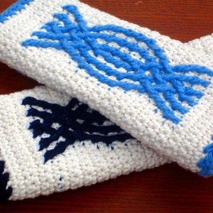 May include: Two white crocheted pot holders with blue and black geometric designs. The pot holders have a white background with blue and black yarn woven into a geometric pattern.