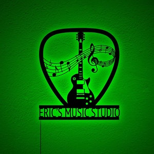 May include: Black silhouette of an electric guitar with musical notes and a treble clef inside a pick shape. The text "ERIC'S MUSIC STUDIO" is below the pick shape.