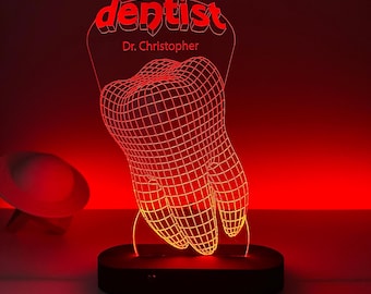 May include: A red illuminated dentist-themed lamp. The lamp features a wireframe tooth design and the word "dentist" in red, along with the name "Dr. Christopher". The lamp sits on a black base and emits a warm red glow.