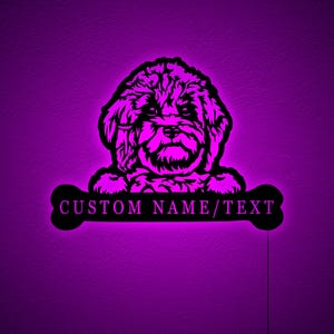 Puede incluir: Una luz nocturna iluminada de color morado que presenta la silueta de un perro con una forma de hueso debajo. El hueso tiene el texto "CUSTOM NAME/TEXT" en él.