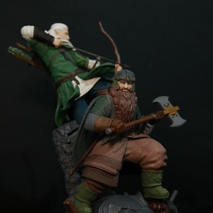 Pode incluir: Uma figura verde e marrom de um anão com barba e machado, em pé sobre uma base de rocha. Uma figura de elfo verde com arco e flecha está atrás do anão. A base tem um design dourado e marrom.