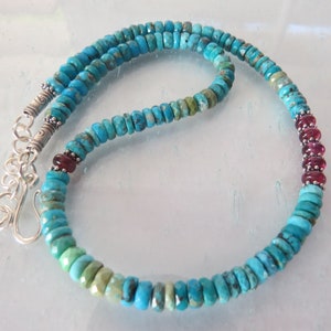 May include: A turquoise and red gemstone necklace with a silver clasp. The necklace is made of small, round beads and features a section of red gemstone beads.