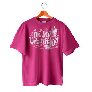 Op de afbeelding: Een roze T-shirt met een witte afbeelding waarop staat "It's My Unbirthday!" met een theekopje en taartontwerp.
