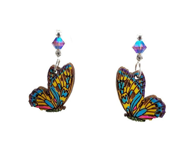 May include: A pair of butterfly earrings. Each earring features a wooden butterfly pendant with yellow, blue, and pink wing details. A small, iridescent crystal bead hangs above each butterfly, attached to a silver-colored hook.