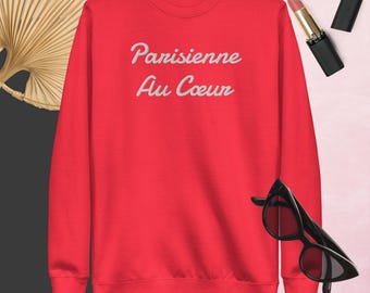 Può includere: Felpa rossa con il testo "Parisienne Au Coeur" in lettere corsive bianche.