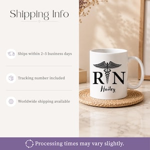 May include: A white ceramic mug featuring a black caduceus symbol positioned between the letters R and N, with the name Hailey printed in a black script font below. The mug has a standard handle and sits on a round, woven, light brown coaster.