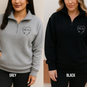 May include: Grey and black quarter-zip sweatshirts. Each sweatshirt has a heart-shaped design with the word "Marites" and a stethoscope. The grey sweatshirt has a front pocket. The word "GREY" is printed at the bottom of the grey sweatshirt. The word "BLACK" is printed at the bottom of the black sweatshirt.