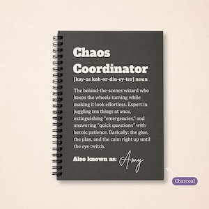 May include: A charcoal spiral-bound notebook featuring white text that defines the term Chaos Coordinator as a behind-the-scenes wizard who keeps wheels turning, juggles tasks, and handles emergencies with patience, ending with the text Also known as: Amy.
