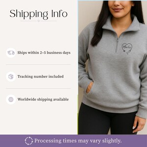 May include: A grey quarter-zip sweatshirt with a front pocket and a small embroidered design on the chest. The design features a heart with a stethoscope and the name "Marites". The sweatshirt is worn by a person wearing black leggings.