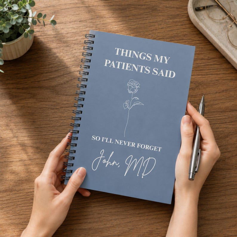 May include: A blue spiral-bound notebook with white text that reads THINGS MY PATIENTS SAID, SO I'LL NEVER FORGET, and John, MD. The cover features a simple white line drawing of a single rose centred between the lines of text.