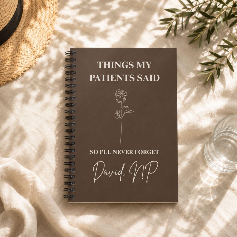 May include: A dark brown spiral-bound notebook featuring the white text THINGS MY PATIENTS SAID, a line-art rose illustration, the text SO I'LL NEVER FORGET, and the name David, NP printed in a white script font on the front cover.