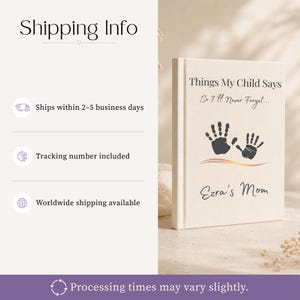 May include: A cream-coloured hardcover book with the title Things My Child Says So I'll Never Forget printed in black text. The cover features two black handprints above a gold wavy line and the name Ezra's Mom in black cursive script.