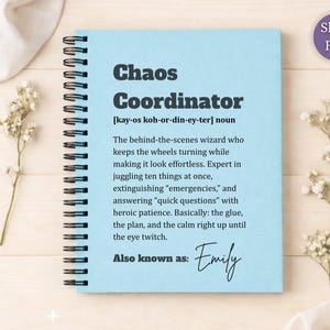 May include: A light blue spiral-bound notebook featuring the text Chaos Coordinator, a phonetic pronunciation, a definition of the term, and the phrase Also known as: Emily in black ink. The cover has a matte finish and a black metal coil binding.