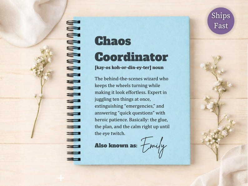 May include: A light blue spiral-bound notebook featuring the text Chaos Coordinator, a phonetic pronunciation, a definition of the term, and the phrase Also known as: Emily in black ink. The cover has a matte finish and a black metal coil binding.