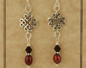 May include: Sterling silver Celtic knot earrings with a dark red bead and a clear crystal bead. The earrings are on a brown card with the text "Celtic Treasures" and "Sterling Silver".