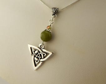 May include: Silver-toned Celtic knot pendant necklace. The pendant is a triangular shape with an intricate knot design. A green bead and small beads are above the pendant. The necklace is on a silver chain.