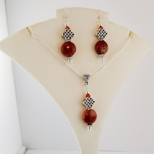 May include: A silver necklace and earrings set with brown stone beads and silver Celtic knot charms.