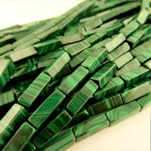May include: A strand of green malachite gemstone beads, each bead is a rectangular prism with a smooth, polished finish.