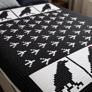 May include: A black and white quilt featuring a repeating pixelated bird pattern across the main surface. The design includes larger rectangular panels at the top and bottom, each displaying a single black bird with a small red eye detail.