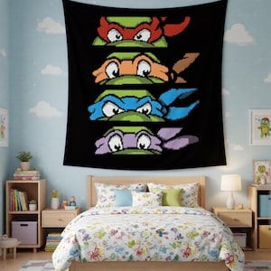 Puede incluir: Un tapiz de pared rectangular negro con un gráfico de arte de píxeles de cuatro personajes de tortuga verdes. Cada personaje se muestra desde los ojos hacia arriba, usando una máscara de un color diferente: rojo, naranja, azul y morado, apilados.