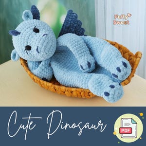 May include: A light blue crocheted dinosaur toy with dark blue accents, including horns, wings, and paw pads. The dinosaur is lying in a woven basket. The text "Cute Dinosaur" is displayed on a dark blue background.