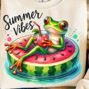 Könnte beinhalten: Cremefarbenes Sweatshirt mit einer Cartoon-Froschfigur, die sich auf einem Wassermelonen-Schwimmring entspannt und ein Getränk hält. Der Frosch ist grün mit orangefarbenen Füßen und großen Augen. Der Text "Summer Vibes" ist in Schwarz geschrieben.