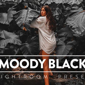 May include: A white button-down shirt worn by a person standing among large, dark, monochromatic tropical leaves. The image features a white rectangular frame containing the bold white text MOODY BLACK and the smaller text LIGHTROOM PRESET.