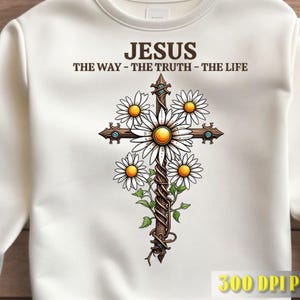 Könnte beinhalten: Ein cremefarbenes Sweatshirt mit Rundhalsausschnitt und einer Grafik eines Holzkreuzes, das mit Ranken umwickelt und mit weißen Gänseblümchen verziert ist. Über dem Kreuz steht der Text JESUS THE WAY - THE TRUTH - THE LIFE. Mit kleinen blauen Akzenten.