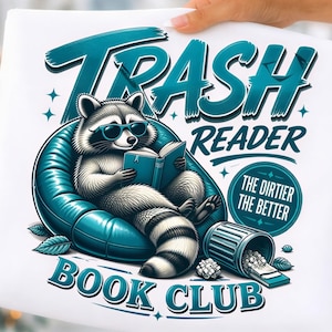 Könnte beinhalten: Ein weißes T-Shirt mit einer Grafik eines Waschbären mit Sonnenbrille, der in einem türkisfarbenen aufblasbaren Sessel sitzt und ein Buch liest. Der Text lautet TRASH READER BOOK CLUB und THE DIRTIER THE BETTER, ergänzt durch eine Mülltonne.