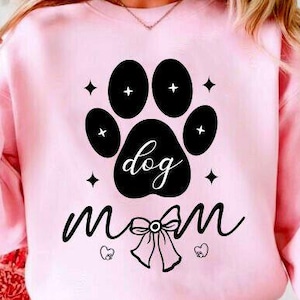 Könnte beinhalten: Hellrosa Sweatshirt mit einem schwarzen Pfotenabdruck-Design mit den Worten "dog mom". Der Pfotenabdruck enthält das Wort "dog". Das Wort "mom" ist darunter in Schreibschrift geschrieben, mit einer Schleife und Herzen.