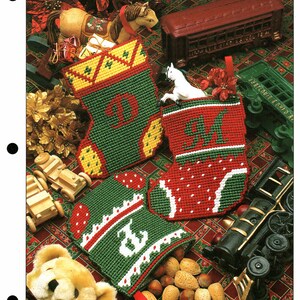 May include: A page titled "Mini Stockings" featuring three handmade Christmas stockings in green, red, and yellow. The stockings are decorated with letters and patterns. The page also includes toy trains, a teddy bear, and a toy horse.