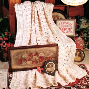 May include: A cream-colored afghan with a shell pattern, draped over a wooden chair. The image features the text "Victorian Elegance" and "Afghan Collector's Series." Additional items include a framed artwork and a small portrait.