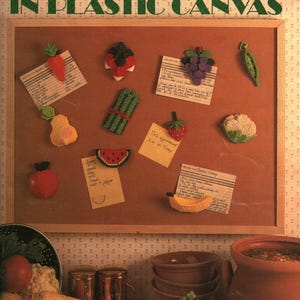 May include: A craft leaflet titled Magnets Take Shape In Plastic Canvas, featuring instructions for creating various fruit and vegetable-shaped magnets. The cover displays finished plastic canvas projects including a carrot, grapes, and corn.