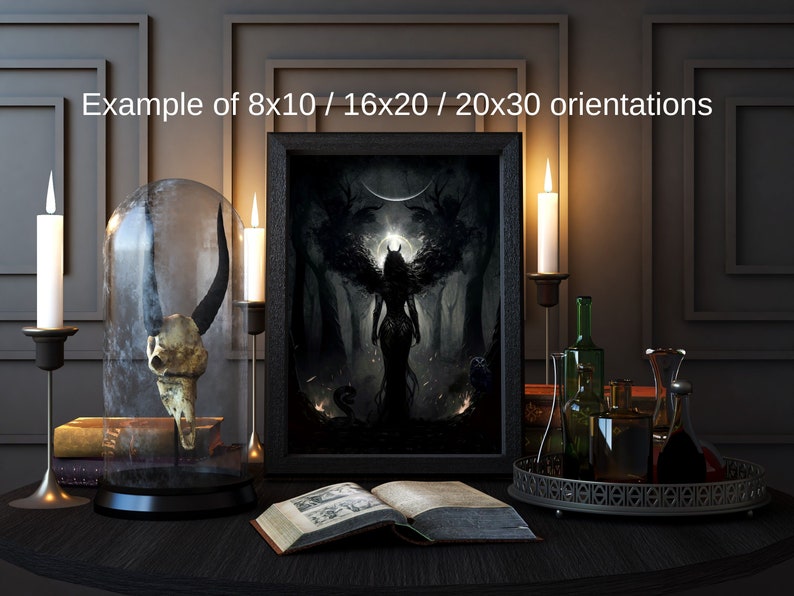 May include: A black framed print of a dark fantasy illustration depicting a winged figure with glowing eyes standing in a forest. The print is displayed on a table with candles, a glass dome containing a skull, and a book.