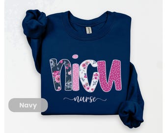 May include: Navy blue sweatshirt featuring the word "NICU" in a floral and polka dot design, with the word "nurse" in a cursive font. The sweatshirt has a crew neck.