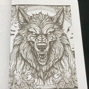 K&ouml;nnte beinhalten: Detaillierte Schwarz-Wei&szlig;-Illustration eines knurrenden Wolfsgesichts mit scharfen Z&auml;hnen und intensiven Augen. Das Kunstwerk ist Teil eines Malbuchs mit komplizierten Mustern und dekorativen Elementen, einschlie&szlig;lich Flederm&auml;usen.