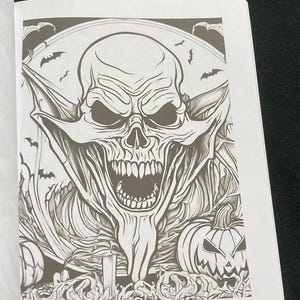 K&ouml;nnte beinhalten: Schwarz-Wei&szlig;-Illustration eines Sch&auml;dels mit offenem Mund, umgeben von Flederm&auml;usen und K&uuml;rbissen. Das Bild stammt aus einem Malbuch mit Halloween-Motiven.