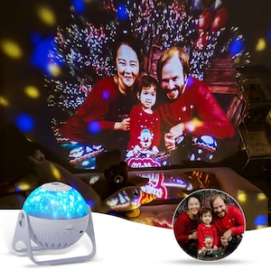Könnte beinhalten: Ein weißer Projektor mit blauem Licht und einem Sternenmuster. Der Projektor projiziert ein Familienfoto an eine Wand. Das Foto zeigt eine vierköpfige Familie vor einem Weihnachtsbaum.