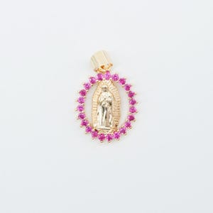 May include: Gold-tone pendant featuring the Virgin Mary, surrounded by a halo of pink gemstones. The pendant has a bail for attaching to a chain. The design is set against a white background.