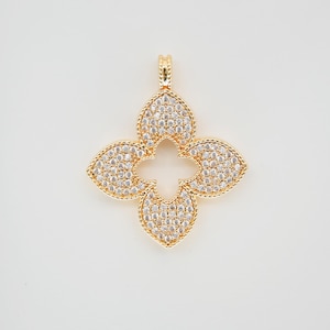 May include: A gold-coloured pendant in the shape of a four-leaf clover. The pendant is encrusted with small, clear gemstones. The edges of the clover are outlined with a textured gold border. The bail is also gold.