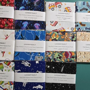 May include: A collection of fabric charm squares, each 5 inches (12.7 cm), featuring various themed patterns. Designs include cherries, jellyfish, fire trucks, socks, gymnasts, superheroes, video game elements, beach scenes, sports equipment, astronauts, and glowing outer space.