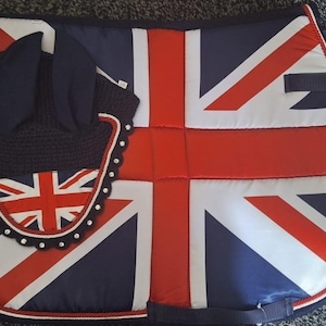 May include: A horse riding set featuring a saddle pad and ear bonnet. The saddle pad displays the Union Jack flag in red, white, and navy blue. The ear bonnet is navy blue with a Union Jack design.
