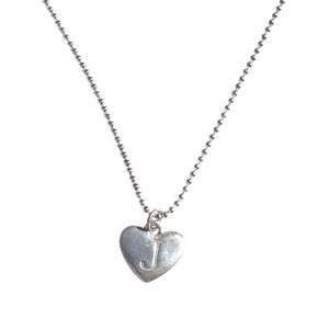 May include: A silver-toned necklace featuring a delicate ball chain and a heart-shaped pendant. The pendant is engraved with the capital letter J in the center. The metal has a smooth, polished finish that reflects light across its curved surface.