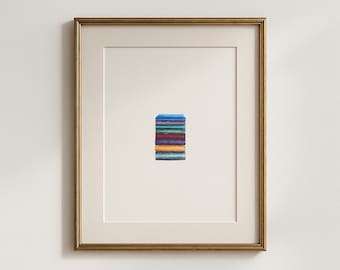 May include: Framed artwork featuring a small, colorful abstract painting. The painting depicts a stack of rectangular shapes in various colors, including blue, green, red, and orange. The artwork is set against a white background and framed in a gold-colored frame.
