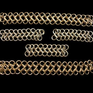 May include: Five pieces of gold chainmail, each with a different length, are arranged on a black background. The chainmail is made of small, interlocking metal rings.