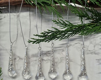 May include: Six silver teardrop-shaped Christmas ornaments with clear glass crystals hanging from silver chains.