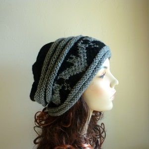 May include: A gray and black knit beanie with a geometric pattern. The beanie is folded down and has a slouchy fit.